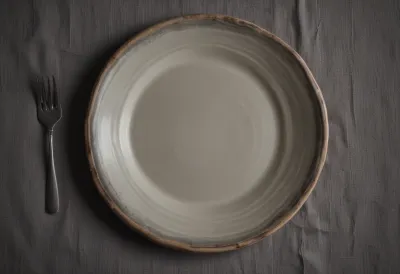 An empty wide handmade ceramic plate with a broad rim on a linen tablecloth