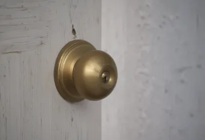 A round brass doorknob on a painted wooden door, close up.