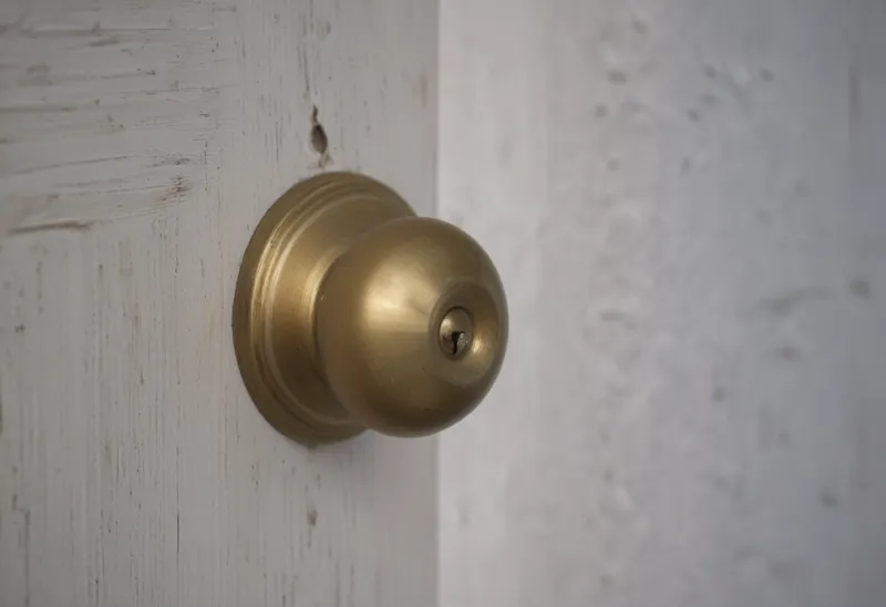 A round brass doorknob on a painted wooden door, close up.
